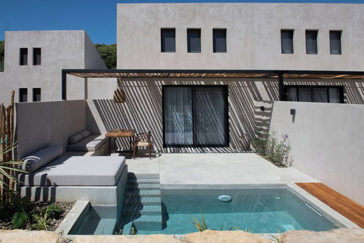 A modern outdoor pool area with a built-in seating area, a small table, and a wooden deck.