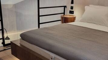 A modern bedroom with a built-in bed, wooden flooring, a bedside table, and a wall-mounted light fixture.