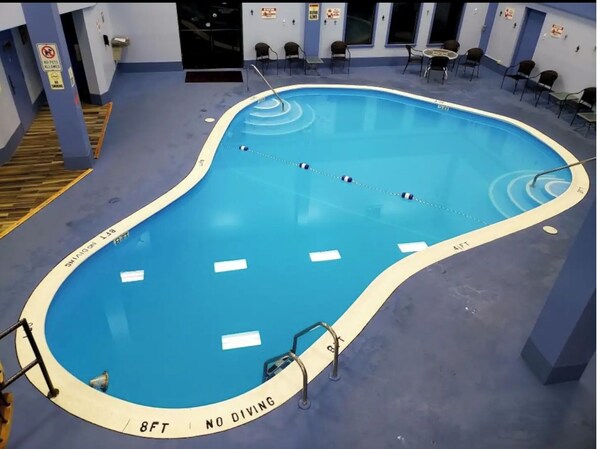En indendørs swimmingpool med et skilt, der viser 'Spring ikke', et skilt, der viser 'Ingen kæledyr tilladt', og et skilt, der viser 'Rygning forbudt'.