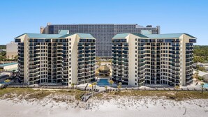 A modern hotel with multiple floors, a central courtyard with a pool, and a beach view.