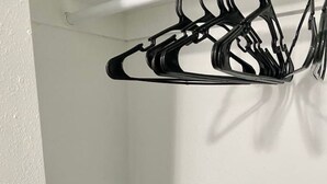 A corner of a room with a white wall, a black hanger, and a grey GRACO bag.