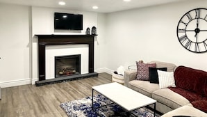 A living room with a fireplace, a sofa, a coffee table, and a wall clock.