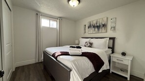 A hotel room with a bed, bedside table, and artwork on the wall.