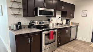 A modern kitchen with dark cabinets, stainless steel appliances, and a granite countertop.