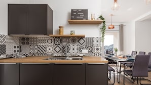Une cuisine moderne dotée d’un îlot central, d’un pare-feu décoratif, de meubles de rangement sombres et d’un coin repas offrant une vue agréable.