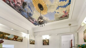 A room with a painted ceiling depicting a sun and clouds, a chandelier, and several framed artworks on the walls. - ART DECO BAYSIDE APARTMENT CLOSE TO THE CITY (Elizabeth Bay)