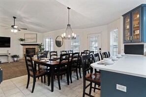 A spacious dining area with a large island, dark wooden chairs, and a chandelier.