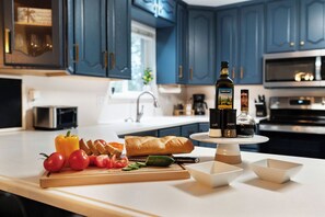 A kitchen with dark blue cabinets, a white countertop, and various food items and condiments.