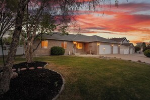 A single-story house with a garage, a well-maintained lawn, and a tree in the foreground.