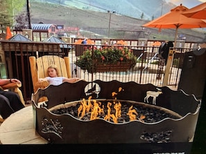 Relax by the fire pit in a cozy outdoor seating area surrounded by lush greenery and comfortable seating.