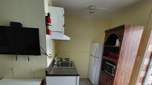 A compact kitchen with a tiled floor, a built-in stove, a sink, and a refrigerator.
