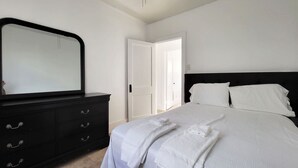 A bedroom with a bed, a dresser, a mirror, and a door.