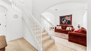 A staircase with white railings leading to a living area with a red couch and a large American flag decoration. - New Listing! Highgate at Legacy Park Resort, 7mi to Disney & 10mi to Universal - FS370169 (Davenport)