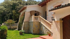 Un bâtiment à deux étages, doté d’une façade en pierre, d’un balcon avec une balustrade et d’une porte en bois.