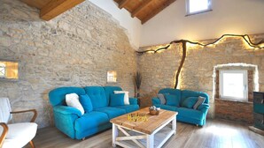 A rustic room with stone walls, wooden beams, and two blue sofas with cushions. - Villa Gisella with heated swimming pool (Nedešćina (Istria))