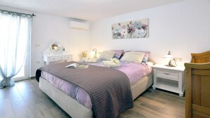 A bedroom with a bed, bedside tables, a dresser, a mirror, and a painting on the wall. - Villa Gisella with heated swimming pool (Nedešćina (Istria))