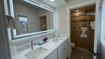 Un bagno moderno con un ampio specchio, due lavabi e cabina doccia in vetro.