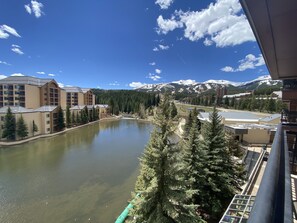 Une vue d’un complexe hôtelier avec un lac, des bâtiments et, au loin, des montagnes aux sommets enneigés.