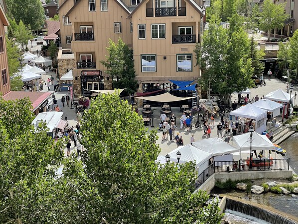 Un marché en plein air installé au bord de la rivière, avec des tentes et beaucoup de monde.
