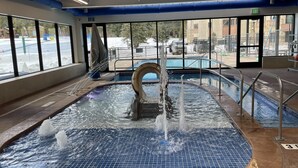 An indoor swimming pool with a central fountain, large windows, and a view of the outside. - Bright Haus Lakeview at the Village at Breck ,Stunning Views, Ski In/Out In Town (Breckenridge)