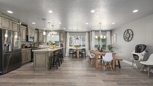 A spacious kitchen with wooden cabinets, a central island, and a dining area with a wooden table and chairs.