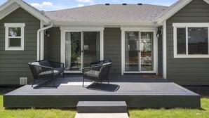 A house with a covered patio area featuring two black chairs and a small table.