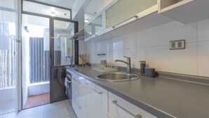 A modern kitchen with white cabinets, a stainless steel sink, and a built-in oven.