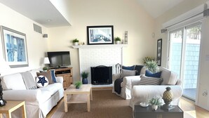 A modern living room with a fireplace, two sofas, a coffee table, and a TV. - Pristine Remsenburg Retreat to Play & Work All Summer Long (Remsenburg)