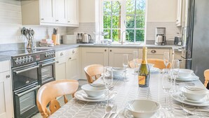 A modern kitchen with a dining area set for a meal. - Middlefield Cottage, rural location close to lake (Coniston)