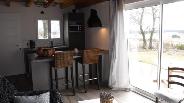 A compact kitchen with a window, a dining area with two stools, and a view of the outdoors.