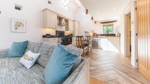 A cozy living room with a sofa and a dining area with chairs and a table. - Mill Pool Barn, stunning riverside barn conversation in idyllic location (Coniston)