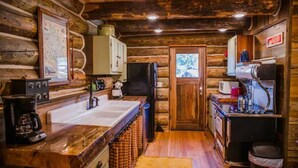 A rustic cabin-style kitchen with wooden walls, a sink, a refrigerator, a coffee maker, and a microwave. - Martin City Log Cabin, just a hop away from Glacier National Park (Martin City)