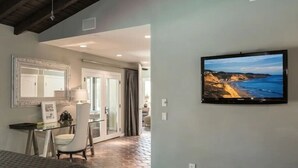 Une chambre d’hôtel avec un lit, un bureau et une chaise, un téléviseur fixé au mur et une vue sur la mer par la fenêtre.