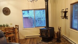 Un accogliente soggiorno con stufa a legna, un lampadario e un'area pranzo con tavolo e sedie in legno.