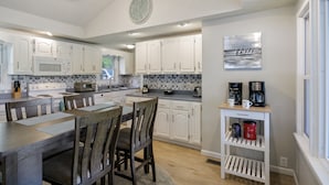 A kitchen with white cabinets, a microwave, a stove, and a dining area with a table and chairs. - AMAZING COVE! 3 Bed/2Ba Lakefront Home - Hot Tub, Smart TVs, EV Charger, Firepit (Eldon)