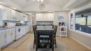 A modern kitchen with white cabinets, a microwave, and a dining table with a 'Catch the Wave' sign. - AMAZING COVE! 3 Bed/2Ba Lakefront Home - Hot Tub, Smart TVs, EV Charger, Firepit (Eldon)