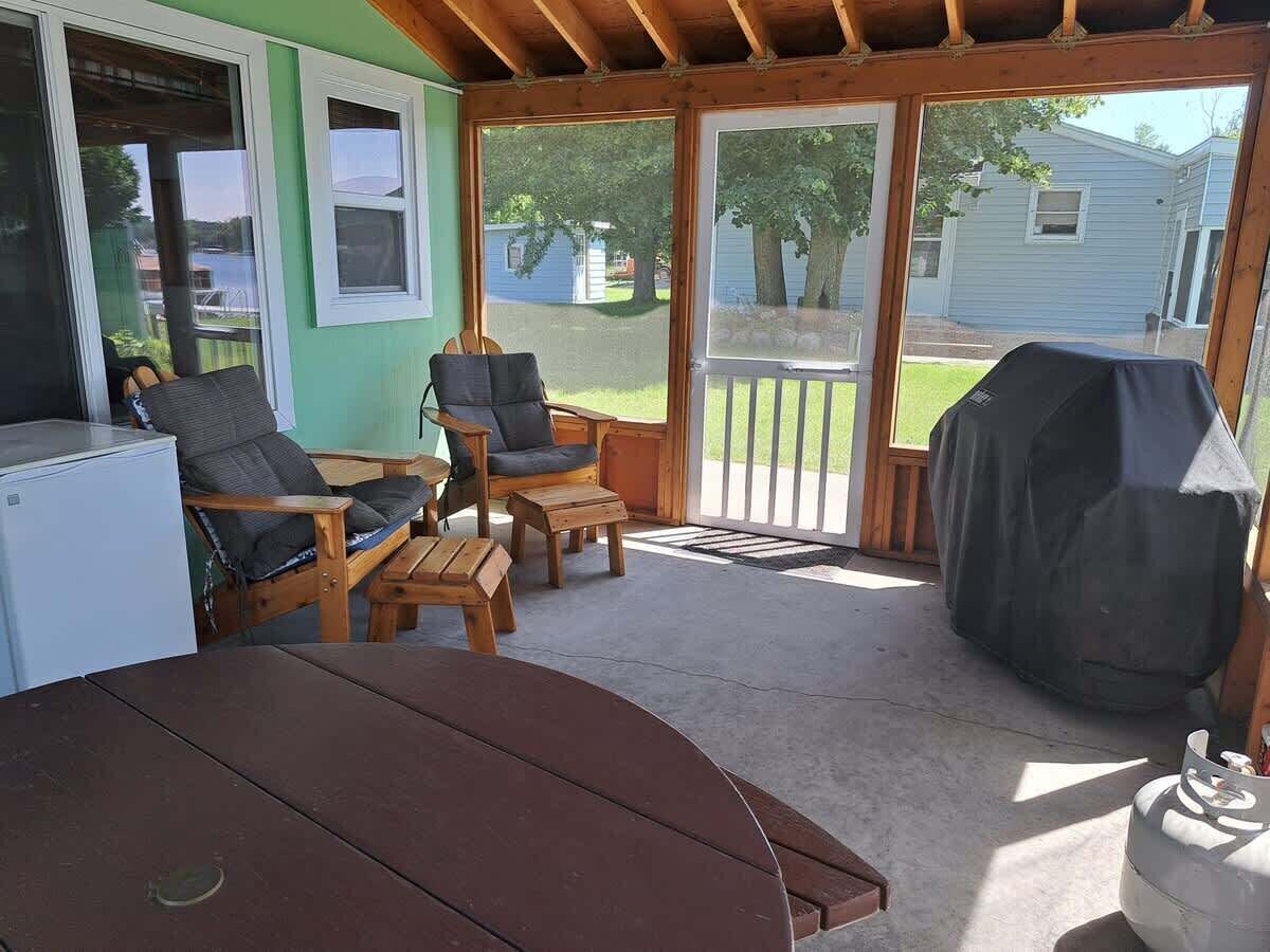 A covered patio with a table, chairs, and a grill.