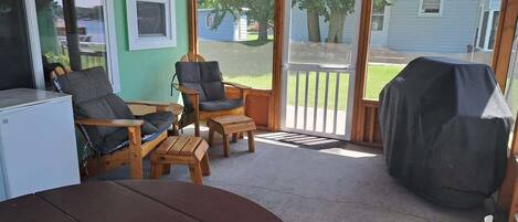 A covered patio with a table, chairs, and a grill.