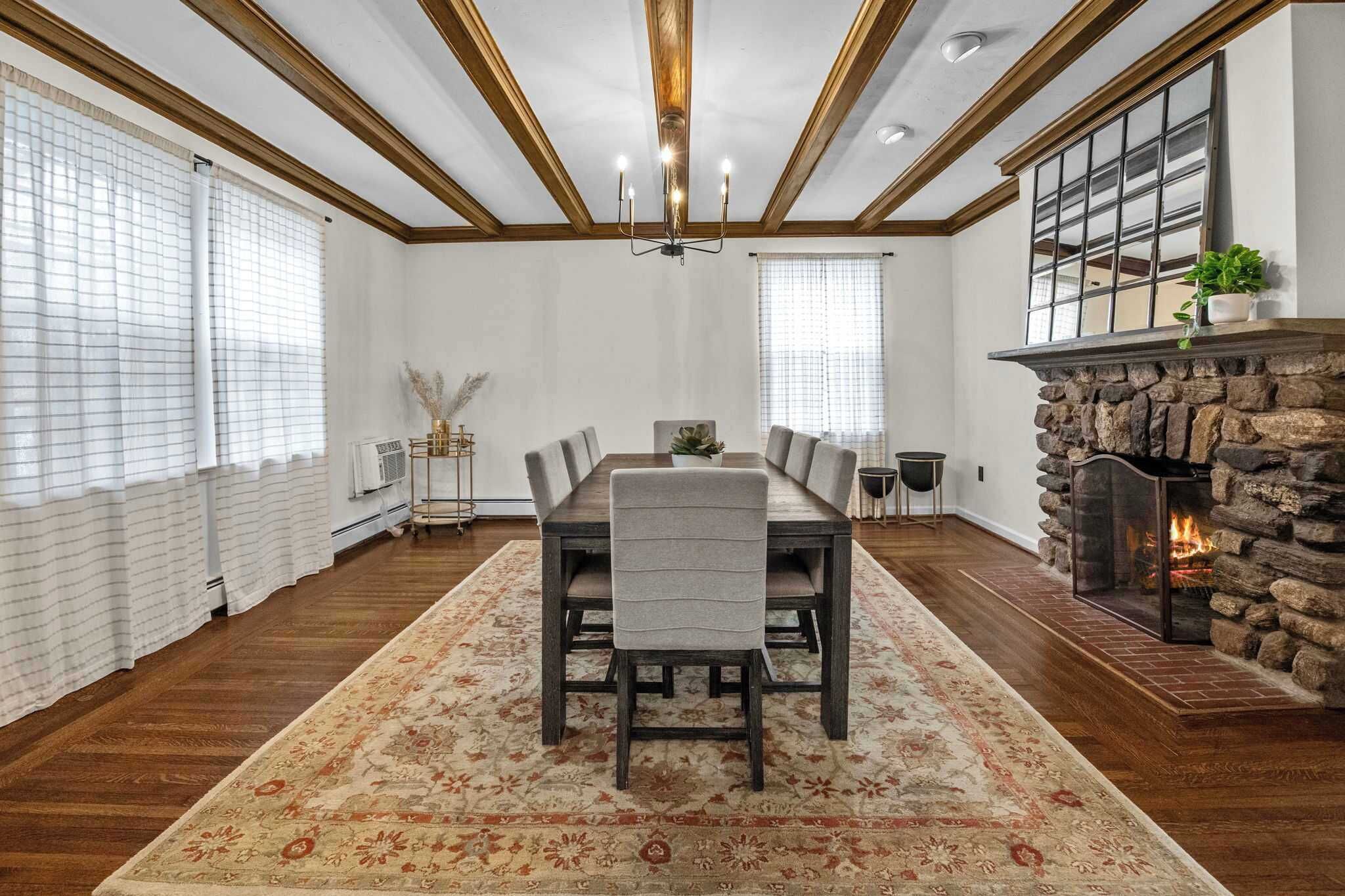 Comedor con una mesa grande, sillas, chimenea y un tapete decorativo.