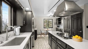 A modern kitchen with dark cabinetry, a stainless steel range hood, a sink, and a countertop with a bowl of lemons. - Spacious 3b/3b Mediterranean in White Plains (White Plains)