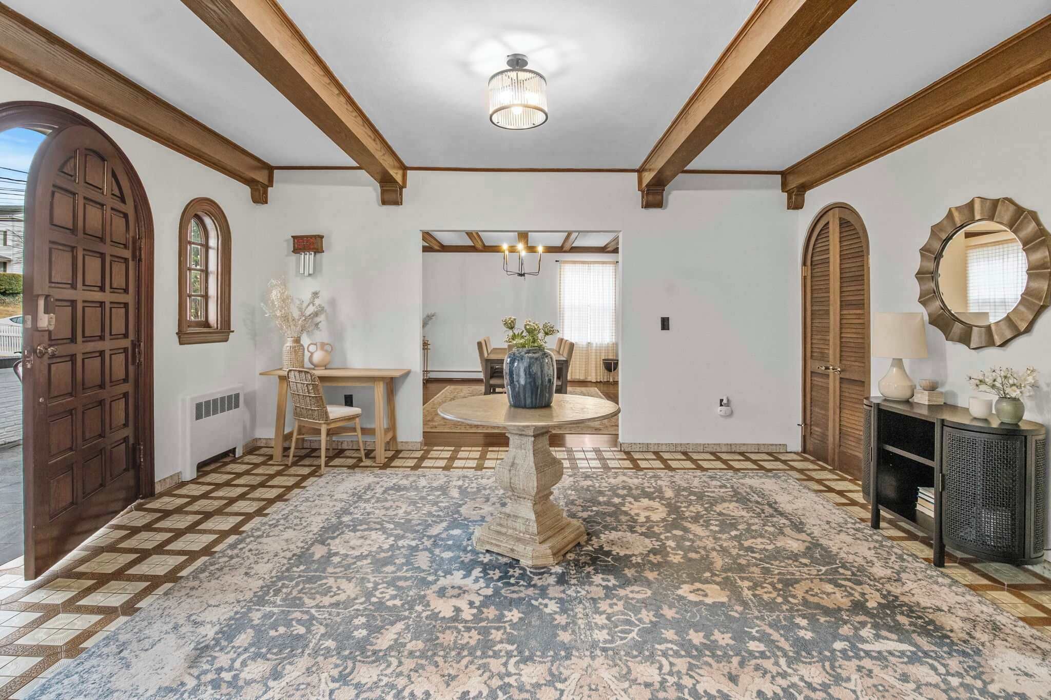 Un interior tradicional con una puerta de madera, una mesa redonda con sillas y una alfombra estampada.