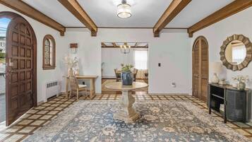 Un interior tradicional con una puerta de madera, una mesa redonda con sillas y una alfombra estampada.