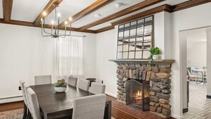 A dining area with a stone fireplace, a chandelier, and a view of the kitchen through a window. - Spacious 3b/3b Mediterranean in White Plains (White Plains)