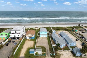 A coastal property with multiple buildings, a parking area, and a beach view.