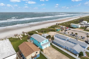 A coastal residential area with beachfront properties, a sandy beach, and a clear view of the ocean.