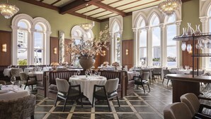 A spacious dining area with high ceilings, large windows, and elegant chandeliers.