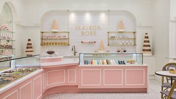 A bakery with a pink counter and display cases, featuring a sign that reads "MAISON ROSE".