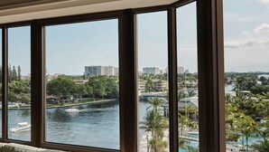 A room with large windows overlooking a river, a cityscape, and a resort area.