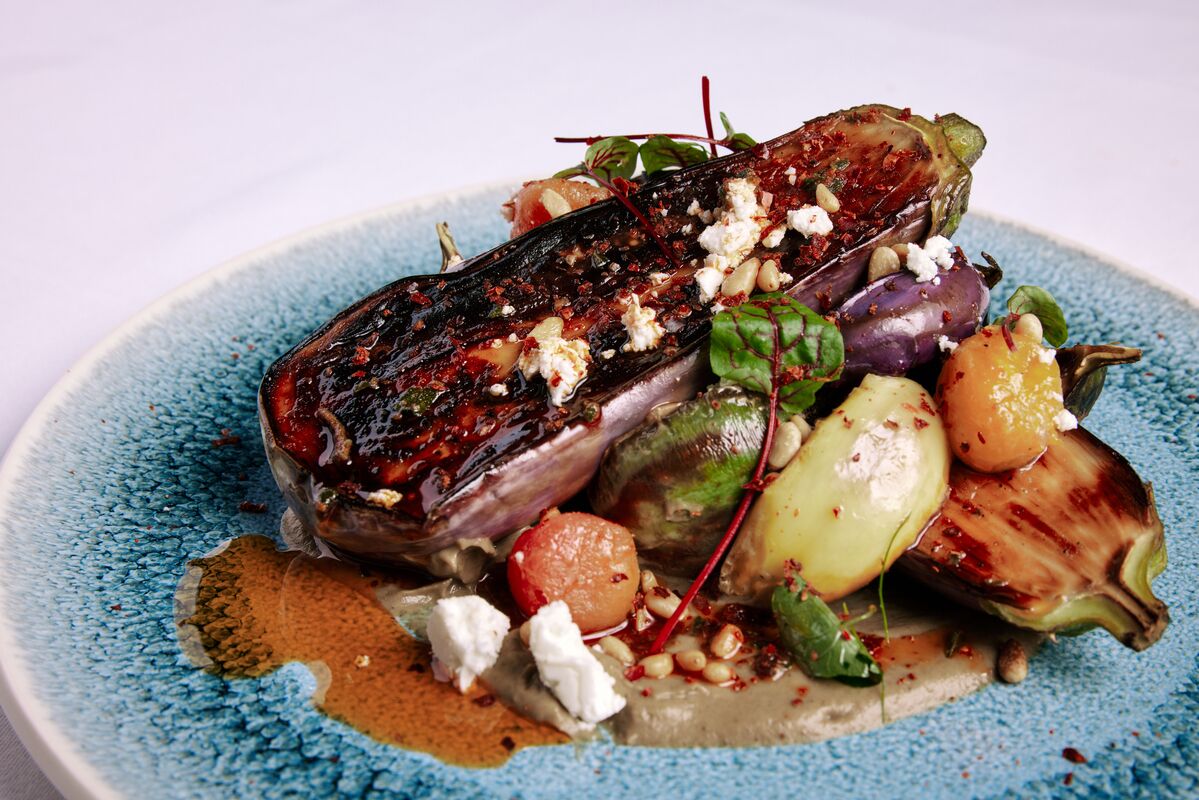 A plate of food with grilled eggplant, feta cheese, and various vegetables.