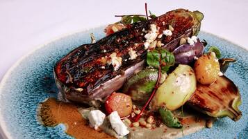 A plate of food with grilled eggplant, feta cheese, and various vegetables.